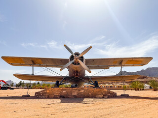 An Old world war one airplane in the middle of the desert under the blue sky and shiny sun