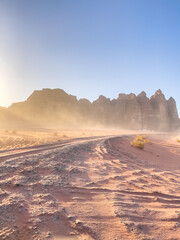Sand storm in the desert under a blue sky and rock formation. Sand dune. Desert landscape