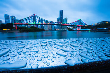 Raindrops on a metal railing with the Story Bridge in the background