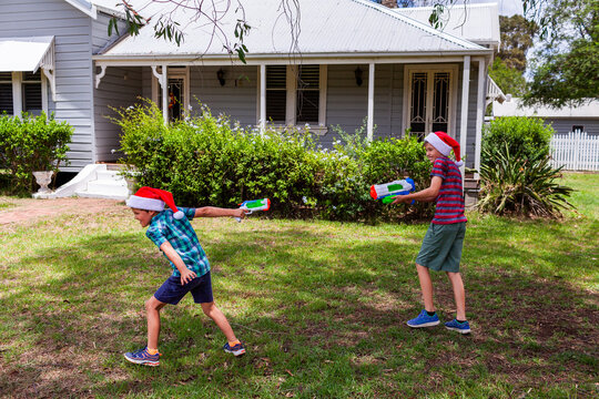 Brothers pointing blaster pistols in Christmastime water fight