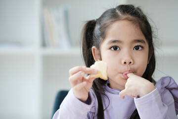 A young girl is eating a piece of fruit