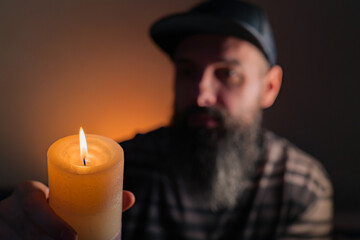Bearded man holding a lit candle in his hand. Orange background