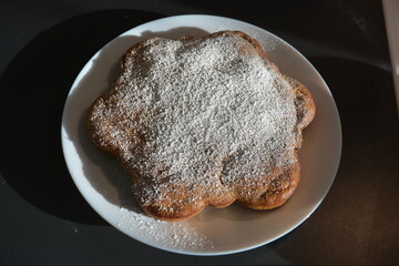 Kitchen, delicious, unusual homemade cake made of banana in the shape of a flower and placed on a white plate.