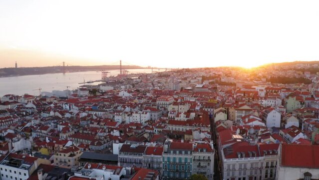 Aerial Panning Scenic View Of Drone, Ponte 25 De Abril Bridge, Drone Flying Over Roofed Houses In City At Sunset - Lisbon, Portugal