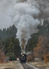 Vintage Steam Train Billowing Smoke and Steam as it Moves Through the Mountains.on a cold and snowy day.