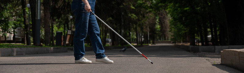 Blind woman crosses the street with the help of a tactile cane. Wide screen. 