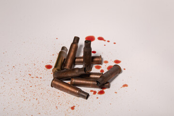 A group of small bullet casings on a white background with drops of blood. concept of war in Ukraine.