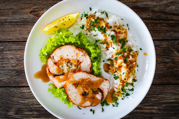 Stuffed turkey breast roulade with dried apricots and cranberries and boiled white rice on wooden table
