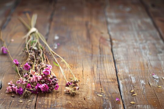 A dried bouquet of small meadow  flowers on an old wooden table.