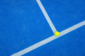 ball on the background line of a blue paddle tennis court