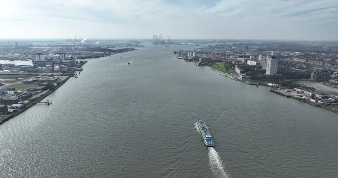 The Nieuwe Maas, runs along Rotterdam, Schiedam en Vlaardingen. This is the port of Rotterdam. Industiral transportation and shipping. Inland shipping vessel aerial drone view. Transport of water.