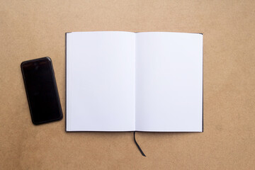 Top view with blank notebook and smartphone on brown wood table