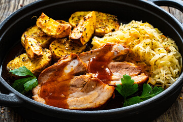 Fototapeta premium Tasty roast ribs with baked potatoes and sauerkraut salad on wooden table 