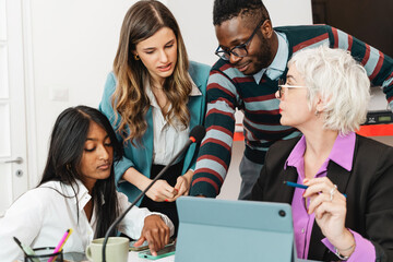 A diverse group of professionals engaged in a collaborative discussion with digital devices - interaction and technology - multicultural office environment, creative brainstorming, teamwork in action.