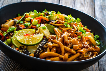 Asian style stir fried vegetables and noodles on wooden table
