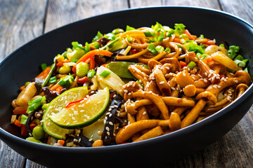Asian style stir fried vegetables and noodles on wooden table
