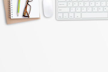 Wireless mouse and mini keyboard with office tools and glasses on white office desk background.