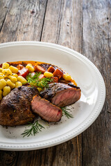 Baked pork cheeks with gnocchi and boiled vegetables in sauce on wooden table
