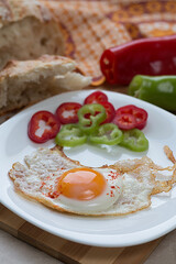 Fried egg on a white plate sprinkled with paprika.