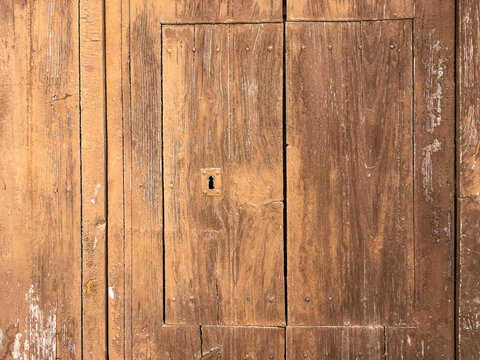 Viejo postigo de una puerta de madera r&uacute;stica en Sanl&uacute;car de Guadiana, Espa&ntilde;a. Cerradura de la puerta cerrada y pintada de marr&oacute;n de una casa antigua y deshabitada.