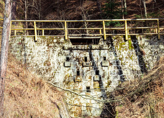 Old stone bridge and dam on creek in forest. Piwniczna-Zdroj, Poland.