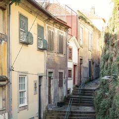 A quaint scene of a back street in Porto, with stone steps running past colourful houses