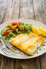 Seared halibut fillet and fresh vegetables on wooden table
