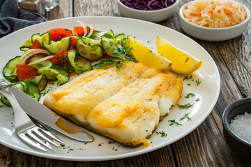 Seared halibut fillet and fresh vegetables on wooden table
