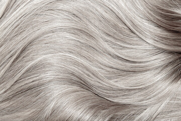 Blond hair close-up as a background. Women's long blonde hair. Beautifully styled wavy shiny curls....