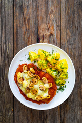 Crispy breaded seared pork chop with fried white mushrooms, cheese and boiled potatoes on wooden table
- 765589829