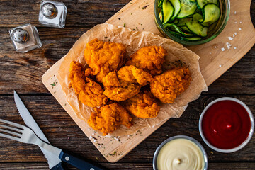 Fried breaded chicken nuggets served with fresh vegetables on wooden table
- 765591082