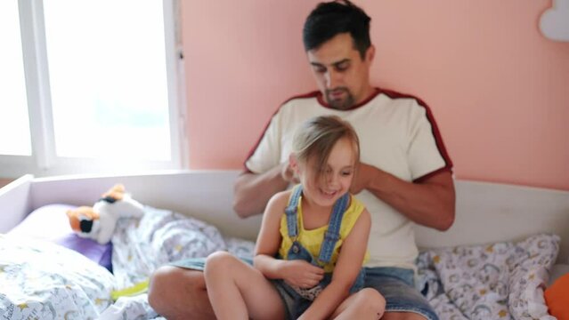 Father braiding his daughter's hair at home