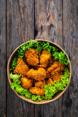Takeaway food - fried breaded chicken nuggets and vegetables on wooden table
