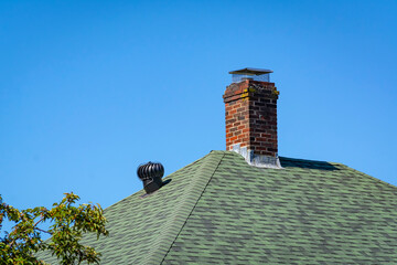 Brick chimney and metal vent on a house shingled roof in Boston, USA