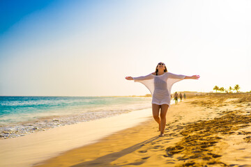 Beautiful woman walking on sunny beach 
