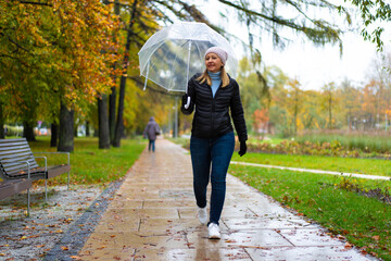 Healthy lifestyle - mid-adult woman walking in city park holding umbrella
- 765605657