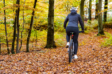 Woman riding bicycle in city forest in autumn scenery
- 765607011