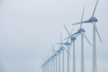 wind turbines in a row on the coast in the mist and fog