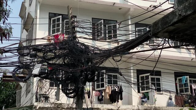 Communications and power transmission cables are seen attached to a street pole in Bangkok, Thailand.