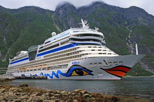 Cruise ship AIDA sol in port of Eidfjord with nice view on the mountains in the Fjord with cloudy horizon