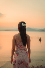 Asian woman in dress with calm mood on the lakeside in the sunset