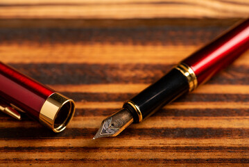 Fountain pen, old and beautiful fountain pen placed on rustic wood and dark background, selective focus.