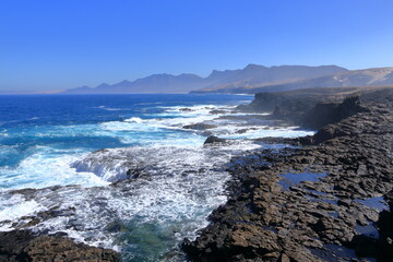 Fototapeta premium Playa de Cofete, Jandia, Fuerteventura, Canary Islands, Spain: Amazing beach behind the with stormy Atlantic Ocean, Volcanic hills in the background