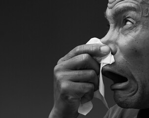 man catching the cold and flu man blowing nose after catching a cold with grey background with...