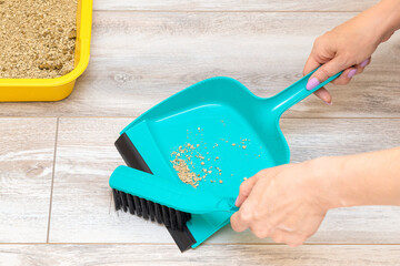 woman sweeping up cat litter from the floor