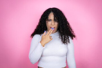 African american woman wearing casual sweater over pink background disgusted with her hand inside...