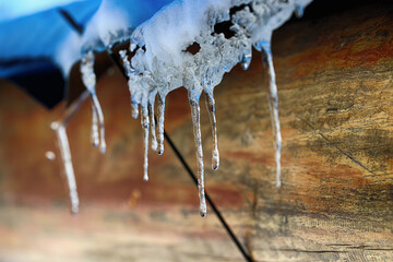 Sopel. Topniejące sople lodowe na zadaszeniu budynku zimą - obrazy, fototapety, plakaty