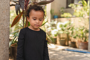 Young Asian toddler frowning and looking down in a garden setting