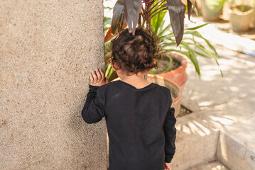 Curious Asian toddler inspecting a bead in a flower pot, unsupervised exploration