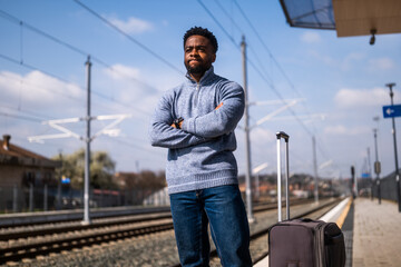 Angry man with a suitcase standing on a railway  station.